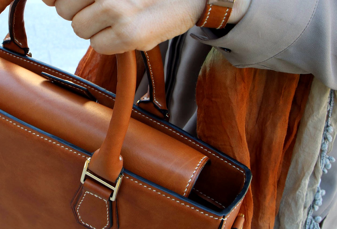 Close-up of premium leather bag making with stitching and hardware details.